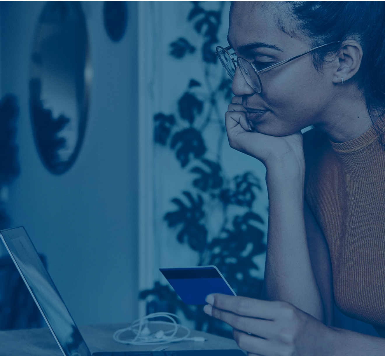 Girl holding card looking at laptop