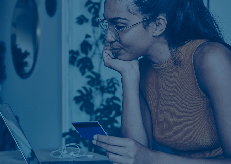 Girl holding card looking at laptop